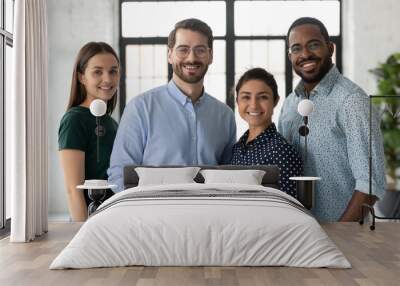 Portrait of successful diverse international business team friendly group of four coworkers capable reliable professional specialists posing at office standing close together smiling looking at camera Wall mural