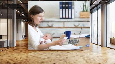 portrait of young business mom holding her newborn cute babe while working in home office interior,  Wall mural