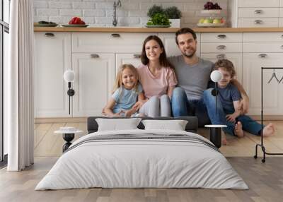 Portrait of young happy family with small children relax on wooden floor in new design kitchen, smiling Caucasian parents rest enjoy leisure weekend with little kids in rent renovated home or studio Wall mural