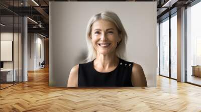 Positive attractive blonde senior woman posing for shooting with perfect toothy smile, standing at camera, laughing. Happy pretty elder retired lady in black cloth head shot video call portrait Wall mural