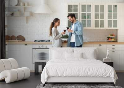 Romantic affectionate young couple drinking wine standing in modern kitchen Wall mural