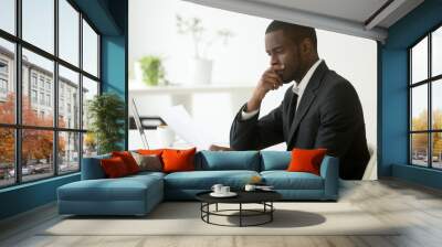 Serious african-american businessman employer thinking of business offer reading mail cover letter at workplace, puzzled black company executive looking at financial document considering contract Wall mural