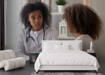 Serious African American female doctor talk to teenage girl sitting at table, focused black woman physician consult teenager, writing down information in patient card. Children health problem concept Wall mural