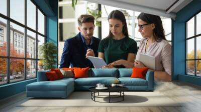 Serious businessman and businesswoman business talking looking at tablet screen. Confident woman leader and colleague discuss joint project development. Teamwork at workplace concept. Wall mural