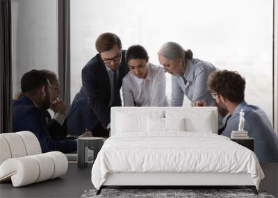 Serious diverse business group discussing project reports at meeting table, reviewing paper documents together. Partners negotiating on startup marketing data Wall mural