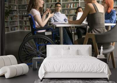 Serious diverse students involved in teamwork and joint tasks gathered in college library, girl with mobility disability explain mathematics problem solution, share ideas for joint essay, cropped view Wall mural