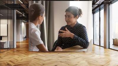 Serious indian mentor worker talk to female colleague teach intern Wall mural