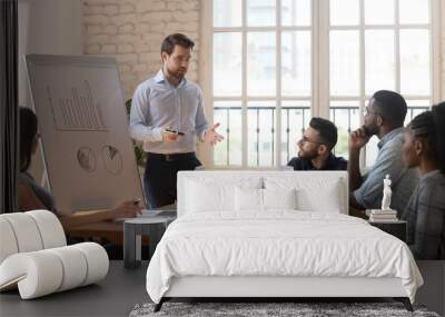 Serious male coach give flip chart presentation to diverse employees Wall mural