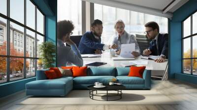 Serious multiracial older and young businesspeople gathered in boardroom discuss financial statistics, analyze sales report, forecasting work together at office meeting. Teamwork, negotiations concept Wall mural