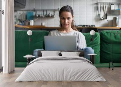 serious woman using laptop checking email news online sitting on sofa, searching for friends in inte Wall mural