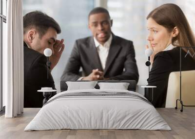 Skeptical female and male caucasian employers covering face with hand and whispering while discussing african american candidate. Disappointed hr managers secretly consulting on failed job interview Wall mural