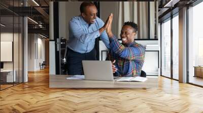 Smiling African American male colleagues give high five celebrate shared business victory or win. Happy ethnic men employees triumph for company success or good job results. Teamwork concept. Wall mural