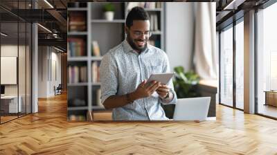 Smiling african business man using digital tablet computer in office Wall mural