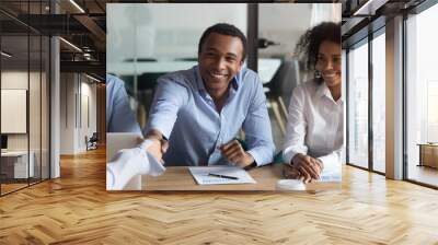 Smiling african manager handshaking greeting caucasian client at group negotiations Wall mural