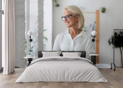 Smiling aged businesswoman look in distance thinking Wall mural