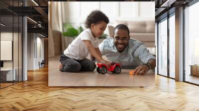 Smiling black dad playing toy cars with little son Wall mural