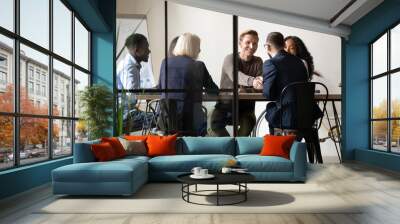 Smiling business partners shaking hands at meeting in boardroom with diverse employees team, making agreement, good legal deal, greeting or introduction, two businessmen handshaking at briefing Wall mural