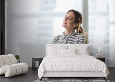 Smiling businesswoman sitting in office chair relaxing with eyes closed, calm female worker or woman ceo feeling peaceful resting at workplace dreaming about positive things distracted from work Wall mural