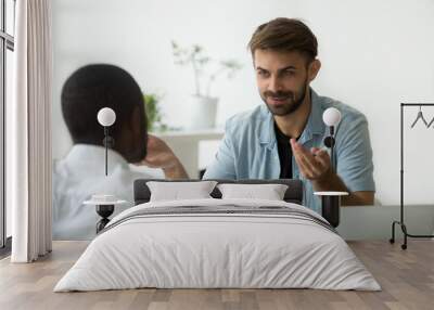 Smiling Caucasian worker talking to African American colleague, explaining business project, discussing financial plan, negotiating at office meeting. Cooperation, teamwork, human resources concept Wall mural