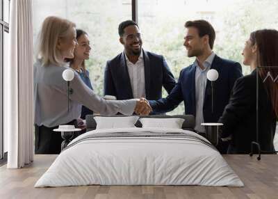 Smiling diverse businesspeople shake hands greeting getting acquainted at office meeting, happy colleagues employees handshake closing deal or making agreement after successful negotiations Wall mural