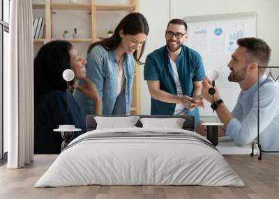 Smiling diverse colleagues gather in boardroom brainstorm discuss financial statistics together, happy multiracial coworkers have fun cooperating working together at office meeting, teamwork concept Wall mural