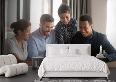 Smiling diverse employees laugh cooperating at laptop in office Wall mural