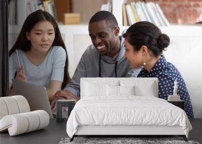 Smiling diverse students talk working on laptop together Wall mural