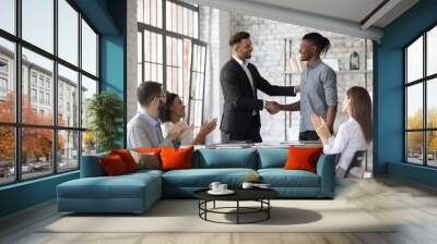 Smiling executive congratulating successful African American employee with promotion, shaking hands at corporate meeting, confident team leader greeting new member at briefing in boardroom Wall mural