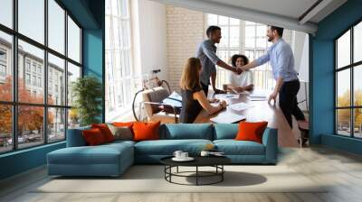 Smiling friendly male boss leader shaking hands with african american intern or employee, praising for good job or welcoming at first meeting. Two male mixed race colleagues establishing partnership Wall mural