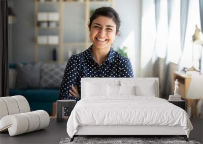 Smiling indian woman looking at camera posing at modern home Wall mural