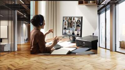 Smiling Indian woman sit at desk at home office talk speak on video call with multiethnic diverse colleagues. Ethnic female employee have webcam digital virtual event on computer with businesspeople. Wall mural