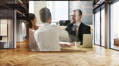 Smiling male realtor or broker shaking hand of excited buyers couple, negotiating about first house purchase or taking loan, insurance agent welcoming clients with handshake at consultation meeting Wall mural