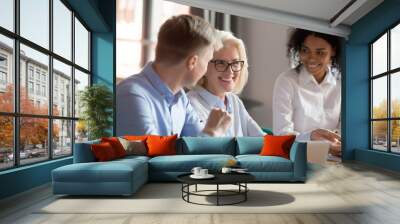 Smiling mature female mentor executive talking at diverse group meeting Wall mural