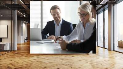 Smiling middle aged older businesswoman signing paper contract at group meeting, happy mature senior woman client puts signature on business document fills form making agreement deal, getting hired Wall mural