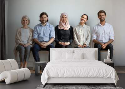 Smiling multicultural professional business people sit on chairs in row Wall mural