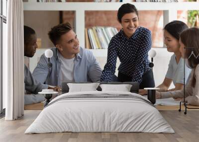 Smiling multiracial diverse students sit ta desk in classroom studying together discuss paperwork project, happy multiethnic young people involved in team activity at lesson in class, teamwork concept Wall mural