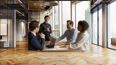 Smiling smart indian female leader holding briefing meeting with diverse business people, discussing marketing strategy or online sales, developing company growth strategy at modern boardroom. Wall mural