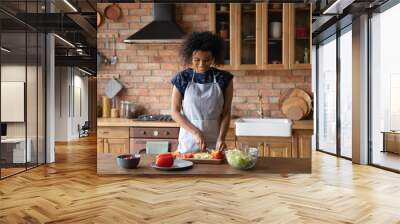 Smiling young African American woman prepare healthy delicious diet dish at home kitchen. Happy millennial biracial housewife cook tasty vegan salad for dinner lunch. Healthy lifestyle concept. Wall mural