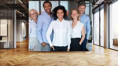 Smiling young african leader looking at camera with diverse team Wall mural