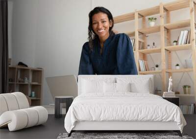 smiling young biracial woman standing at table with computer. Wall mural