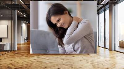 Stiff neck concept, young woman feeling discomfort hurt joint pain rubbing tensed muscles, tired teen girl massaging back to relieve fibromyalgia ache after long computer study in incorrect posture Wall mural