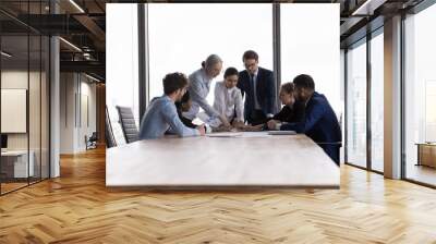 Team of professional diverse business people discuss financial report in charts, diagrams, graphs, analysing sales statistics and deal benefits at group meeting in modern board room, teamwork concept Wall mural