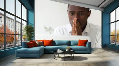 Thoughtful hopeful African American employee looking at computer laptop screen, waiting hoping, person holding hands in praying position, expecting trouble solution, positive result, close up portrait Wall mural