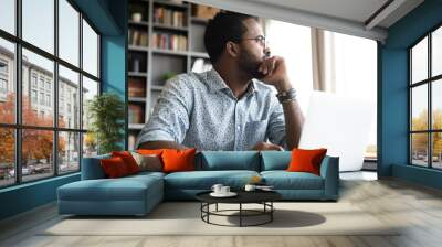 Thoughtful serious african man sit with laptop thinking of project Wall mural