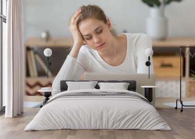 Tired female worker sit at home desk falling asleep working too long at laptop, exhausted girl feel sleepy studying near computer in apartment, young woman sleep at workplace, lacking motivation Wall mural