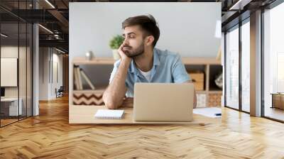 tired male student or worker sit at home office desk look in distance having sleep deprivation, lazy Wall mural