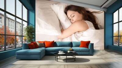 Top view of attractive young woman sleeping well in bed hugging soft white pillow. Teenage girl resting, good night sleep concept. Lady enjoys fresh soft bedding linen and mattress in bedroom Wall mural