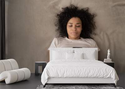 Top view of black girl relaxing in bed using cellphone Wall mural