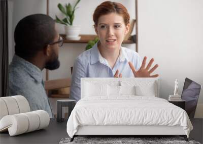 Two diverse businesspeople chatting sitting behind laptop in office Wall mural