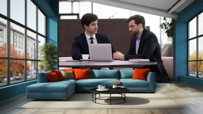 Two serious business men working at new together. Businessmen collaboration. Concentrated office workers colleagues cooperation. Coworkers discuss project, financial plan or strategy using laptop Wall mural